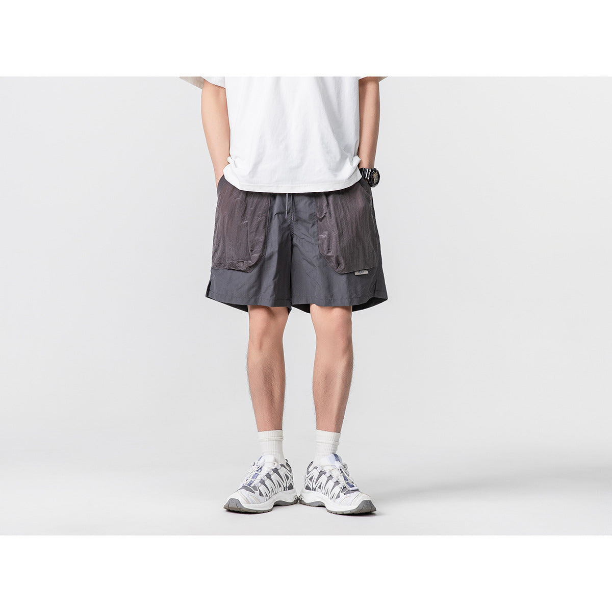 Cropped model wearing charcoal-gray shorts with large contrasting front pockets and a white T-shirt.
