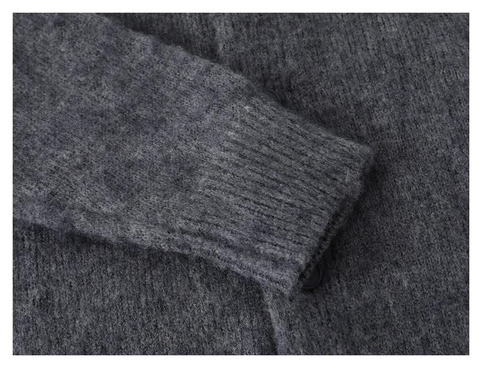 Close-up of a charcoal gray cardigan sleeve and ribbed cuff laid across the body.