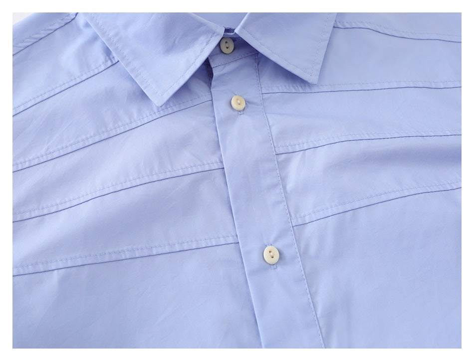 Close-up of the light blue shirt collar, front buttons, placket, and horizontal stitching.