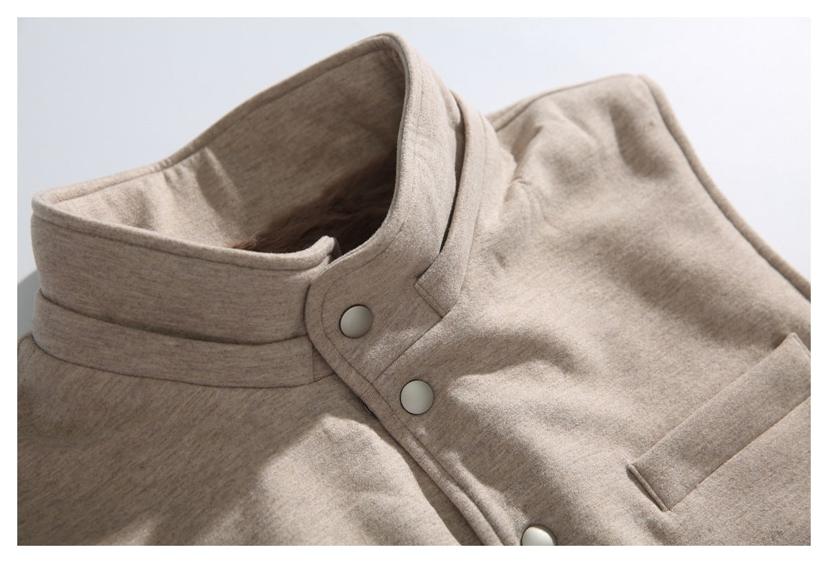 Close-up of the beige jacket's stand collar, snap-front placket, and upper pocket.
