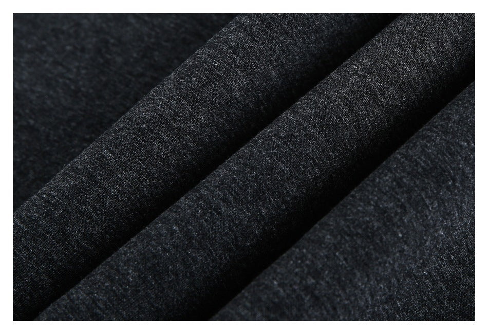 Close-up of dark charcoal heathered fabric draped in soft folds, showing its fine knit texture.