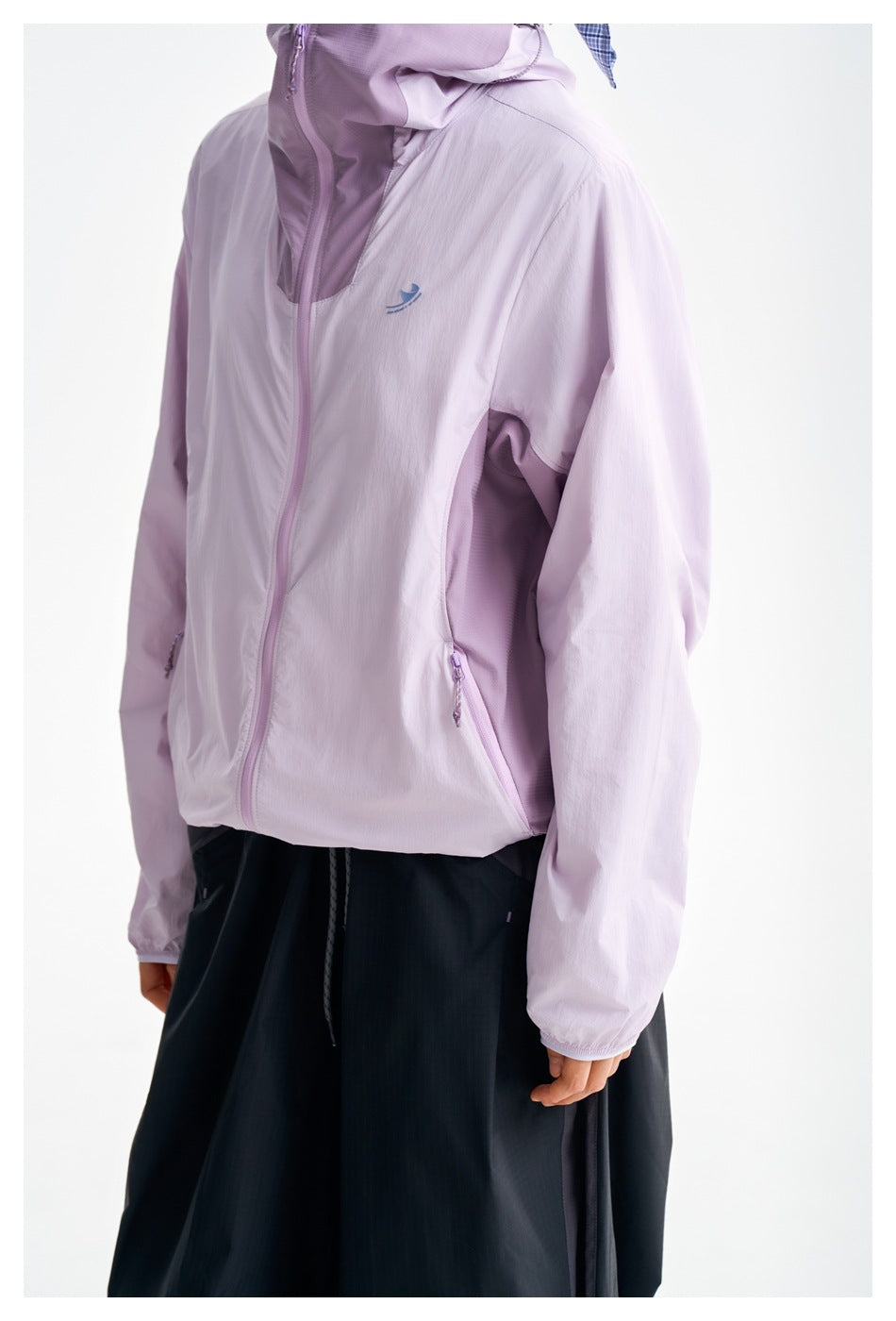 Close view of the lilac jacket's front zipper, chest emblem and zippered side pocket.