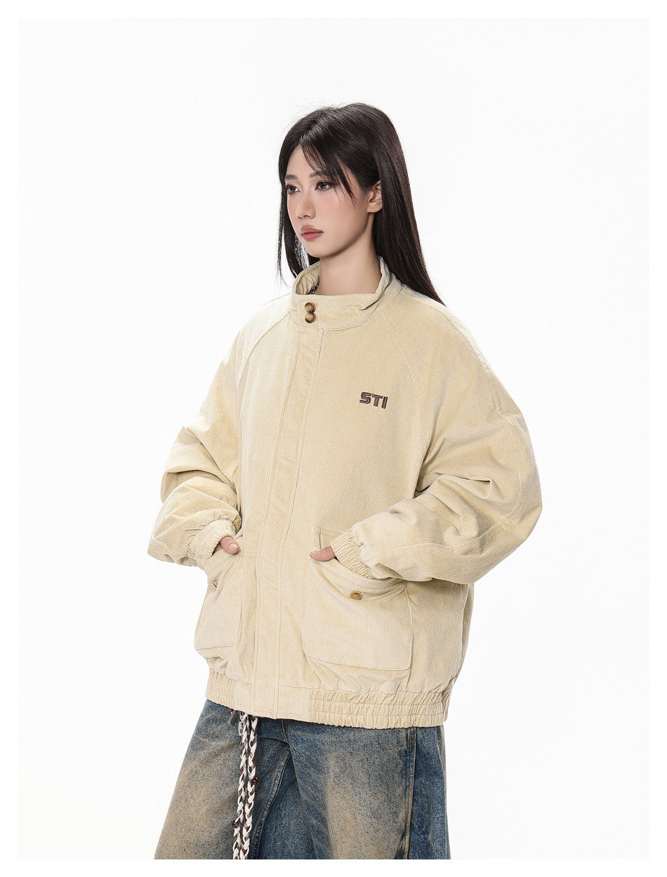 Three-quarter view of a model wearing a beige oversized jacket with a raised collar, gathered cuffs, and flap pockets.