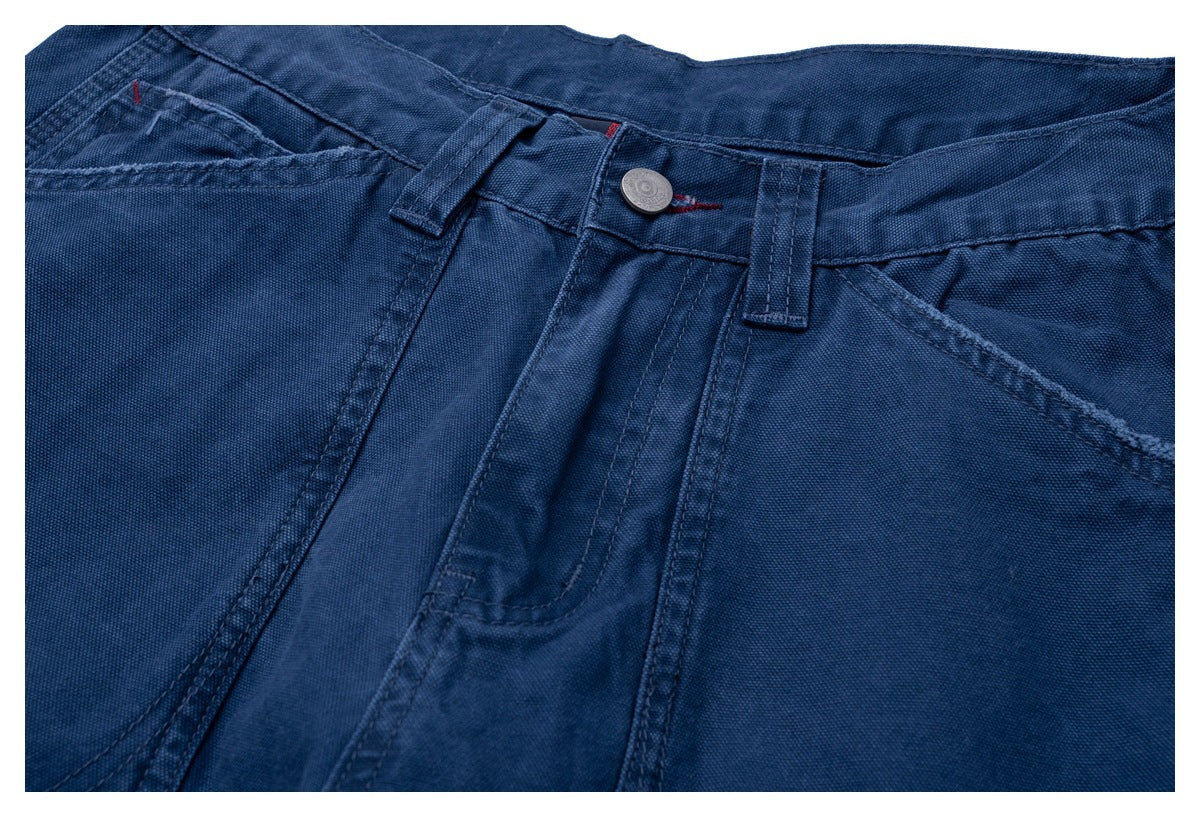 Close-up of the front waistband of dark blue trousers, highlighting the button, belt loops, seams, and pockets.