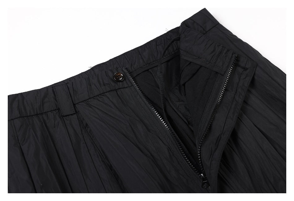 Close-up of black trousers with the waistband unfastened, showing the button and zipper fly.