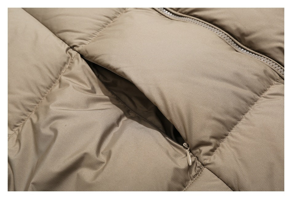 Close-up of a taupe padded jacket showing a diagonal zipper opening and stitched panels.