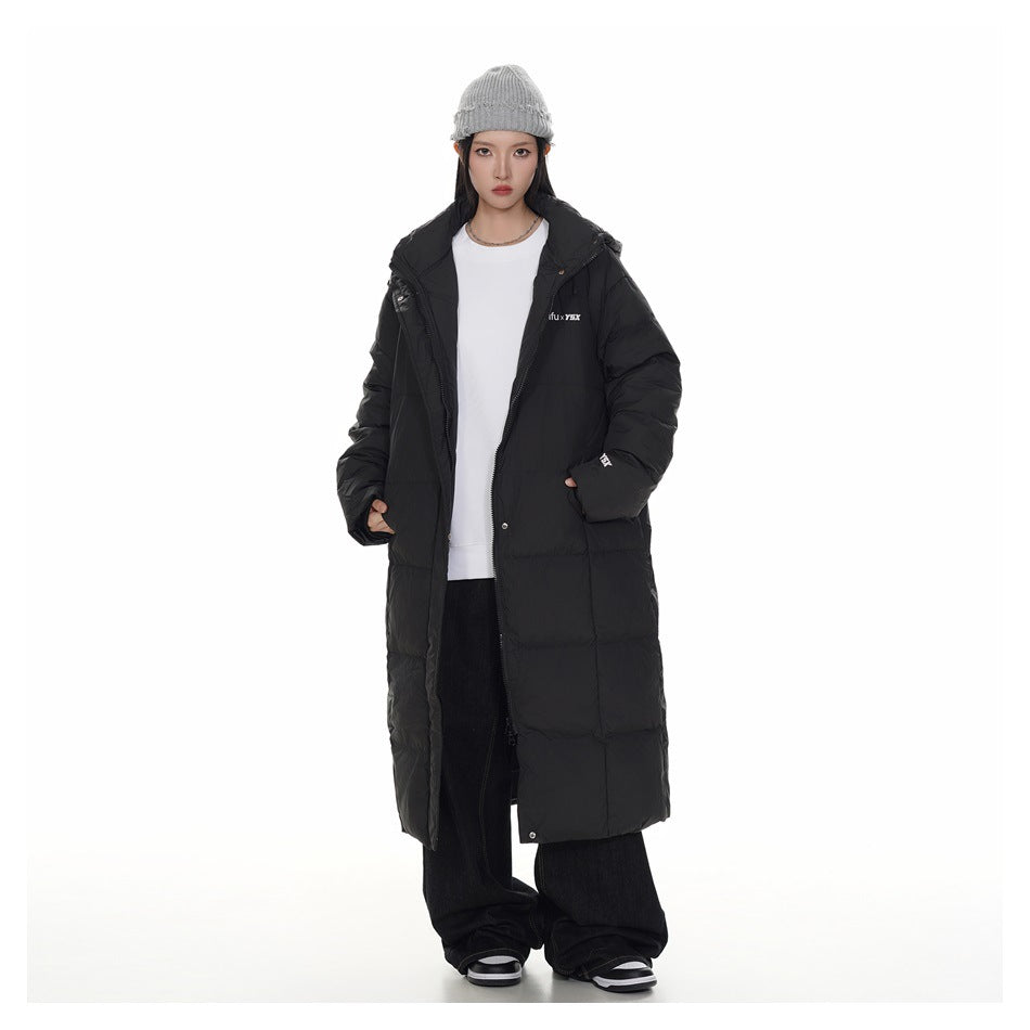 Model wearing an open long black puffer coat over a white top, with a gray knit beanie.
