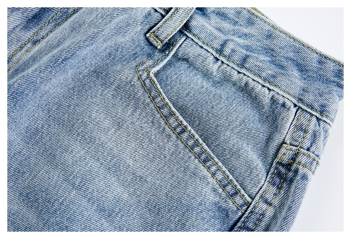 Close-up of a stitched pocket and seams on light-wash blue jeans.
