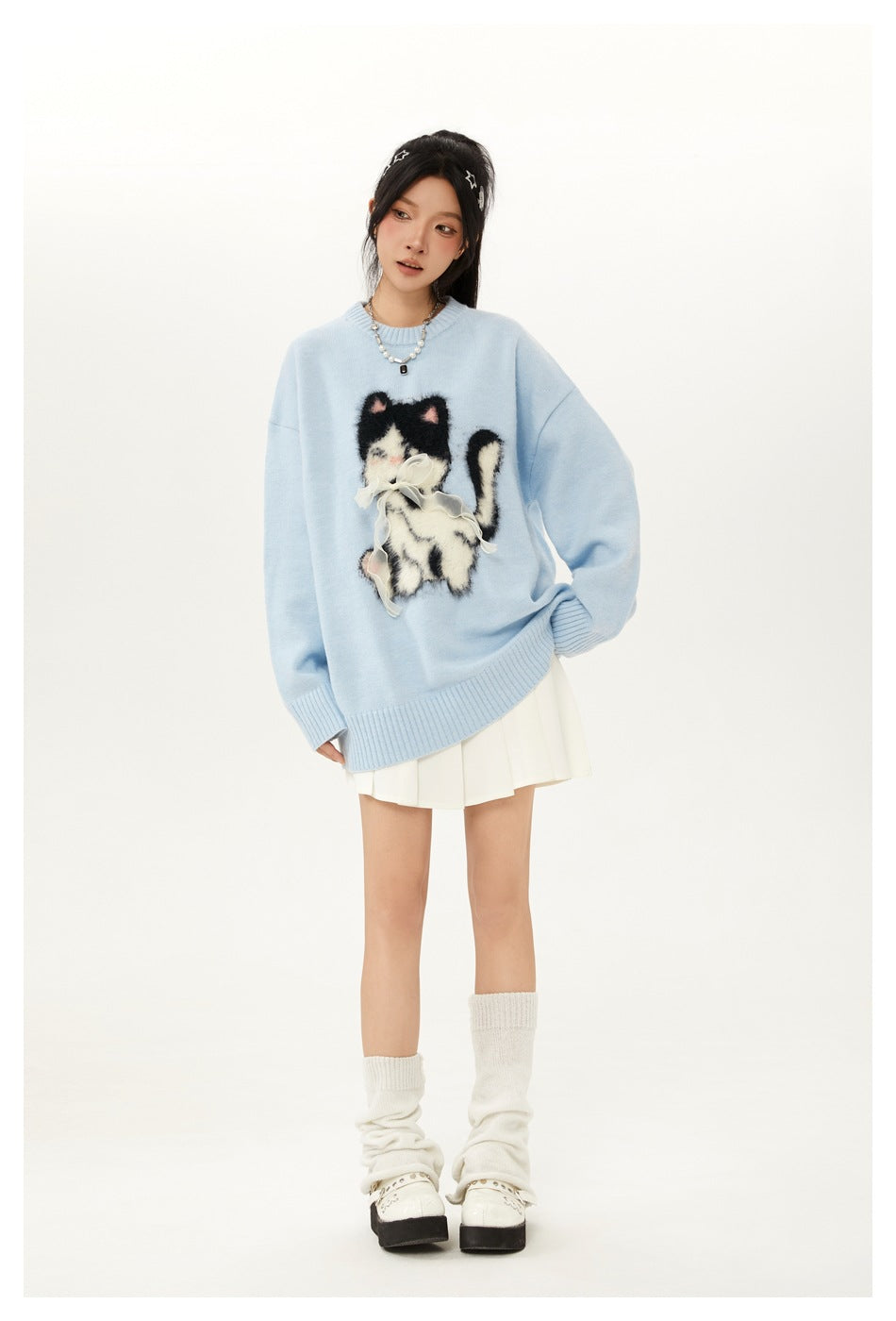 Woman wearing light blue cat motif knit sweater with white pleated mini skirt and white leg warmers