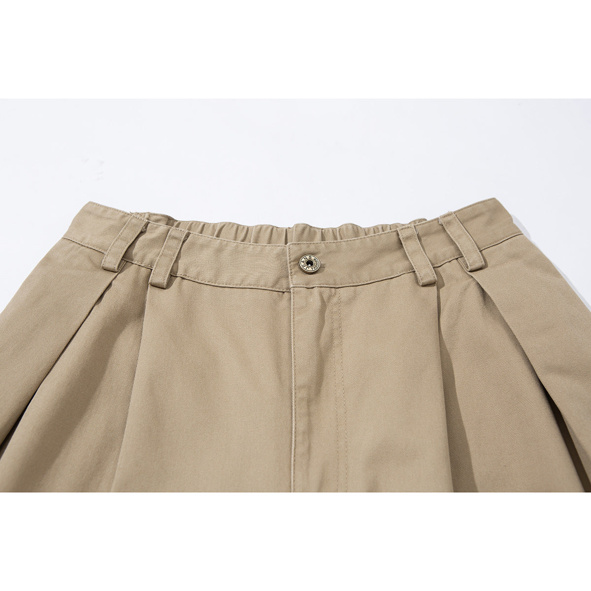 Close-up of tan wide-leg shorts showing the waistband, belt loops, pleats and a metal button.