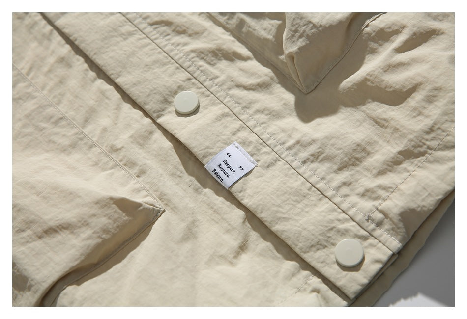 Close-up of the beige jacket's buttoned hem and sewn-in white text label.
