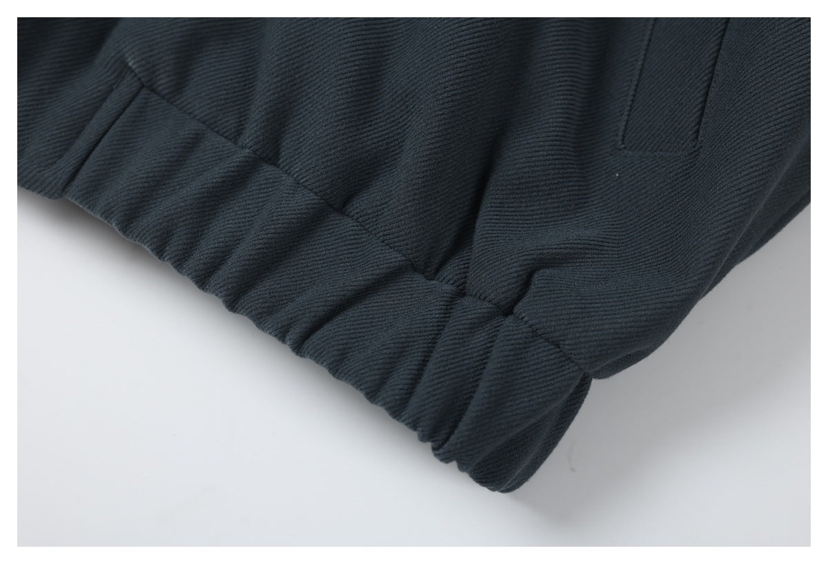 Close-up of a dark charcoal garment with a gathered edge and stitched panel seams.