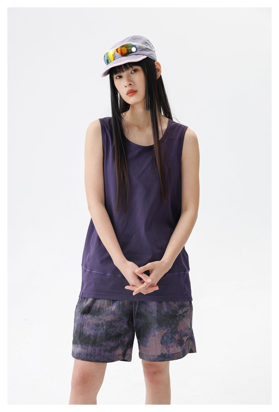 Front view of a model in a dark purple sleeveless top and purple-gray patterned shorts.