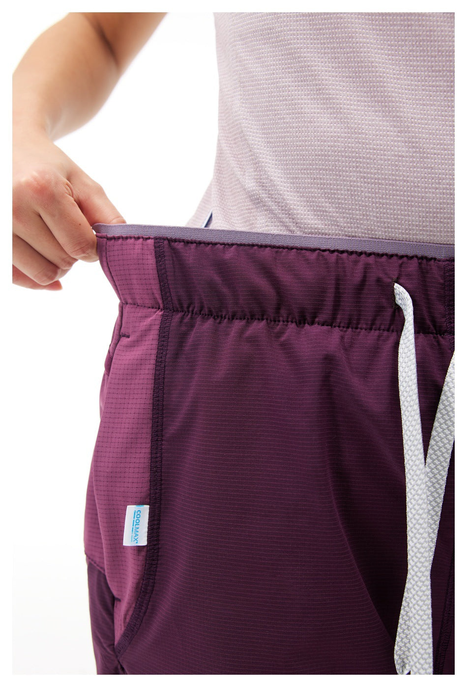Close-up of dark purple shorts waistband, textured grid fabric, side seam tag and white drawstring