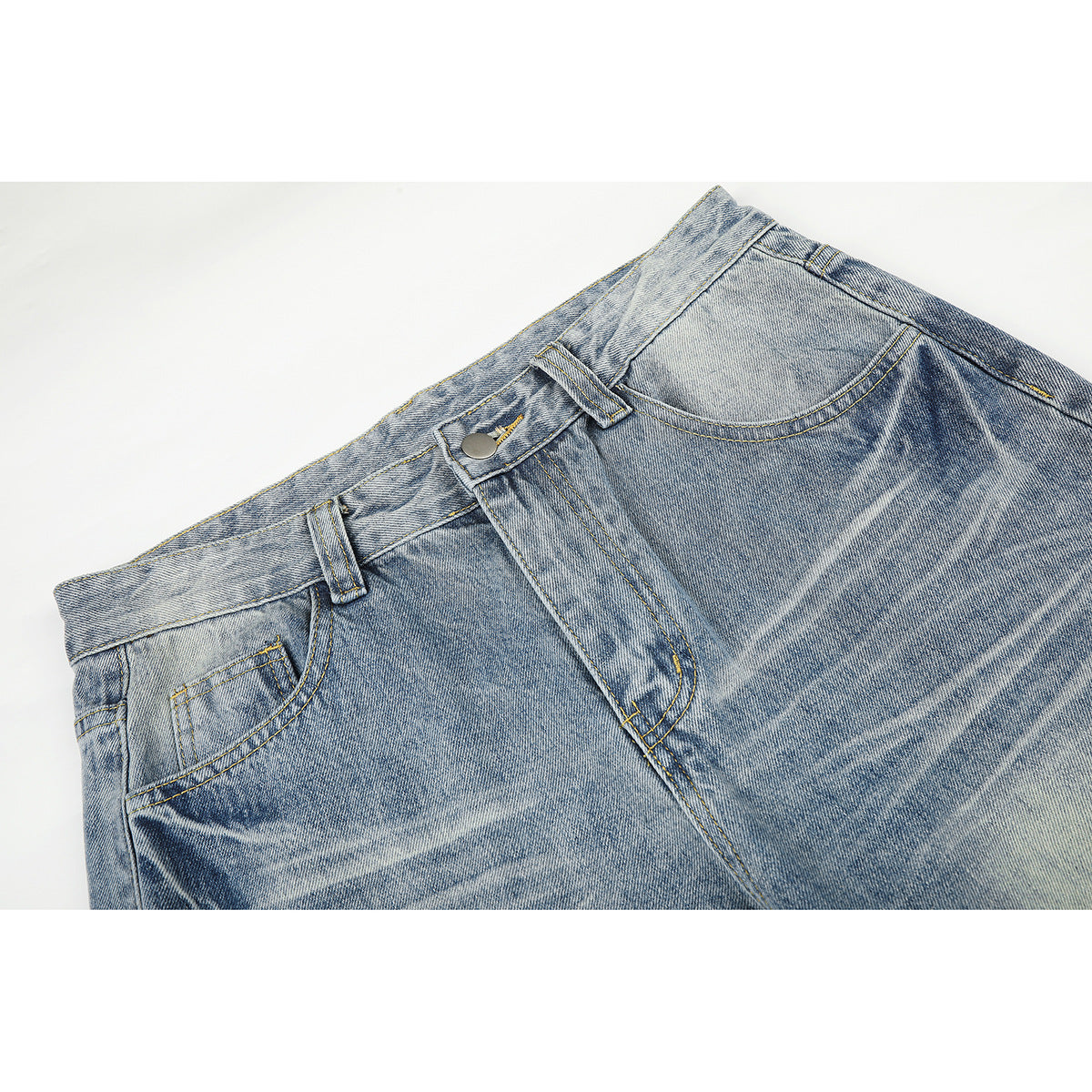 Close-up of light blue washed jeans showing the waistband, button, belt loops, front pocket and contrast stitching.