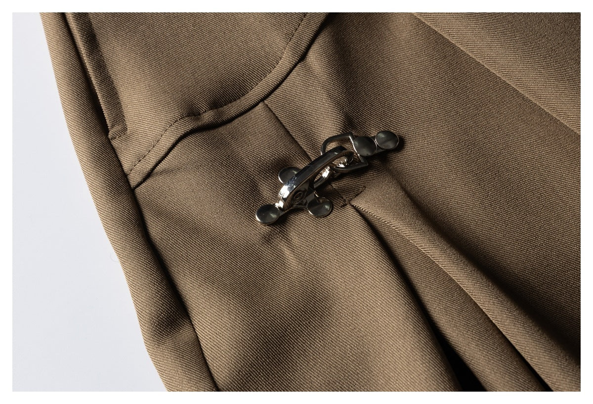 Close-up of a dark metal clasp fastening the front of brown trousers.