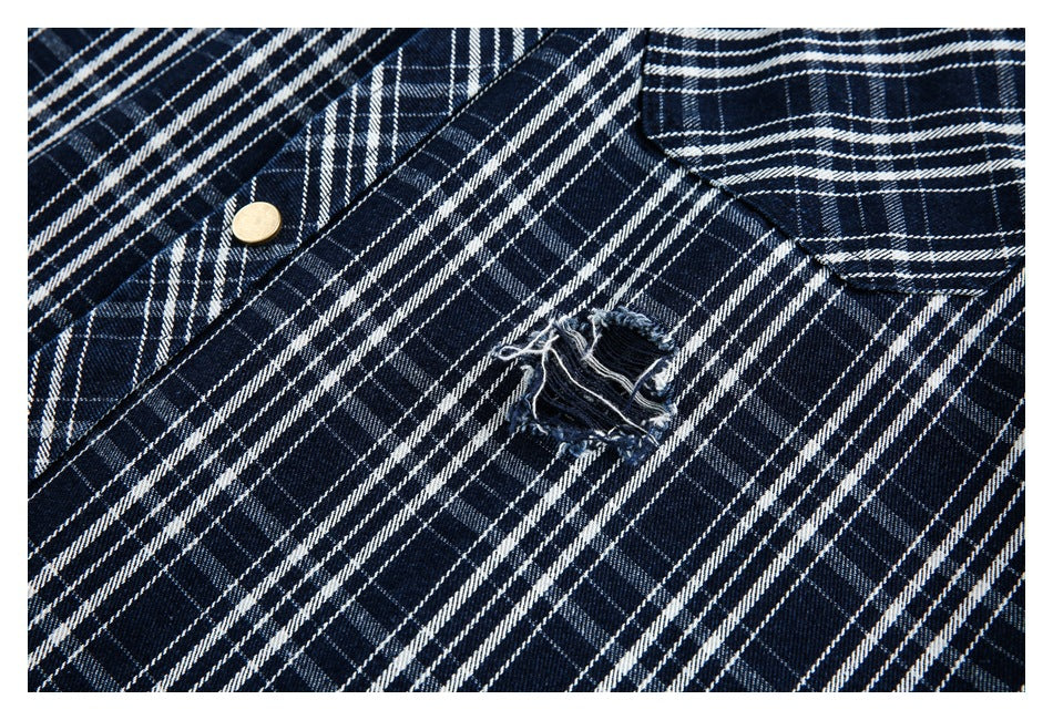 Navy-and-white plaid shirt close-up showing a frayed distressed hole and a brass-colored button.