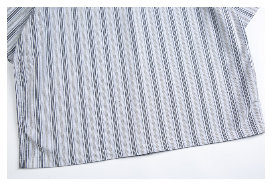Close-up of a light-colored garment hem with narrow gray and blue vertical stripes.