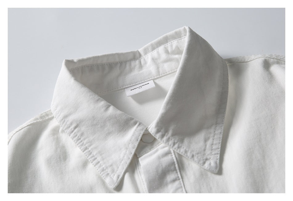 Close-up of a white shirt’s pointed collar, top button and inner neck label.