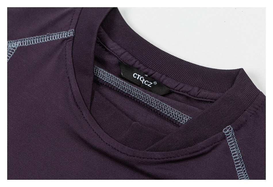 Close-up of a dark plum crew neckline with a brand label and contrasting blue-gray overlock stitching.