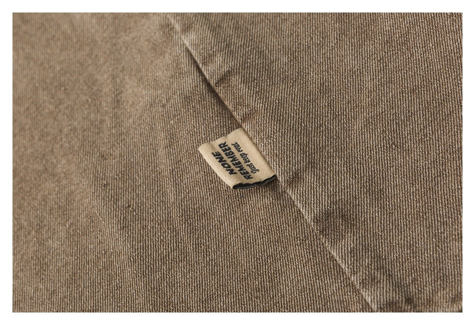 Close-up of brown twill fabric with a small sewn label reading “MOVE FURTHER.”