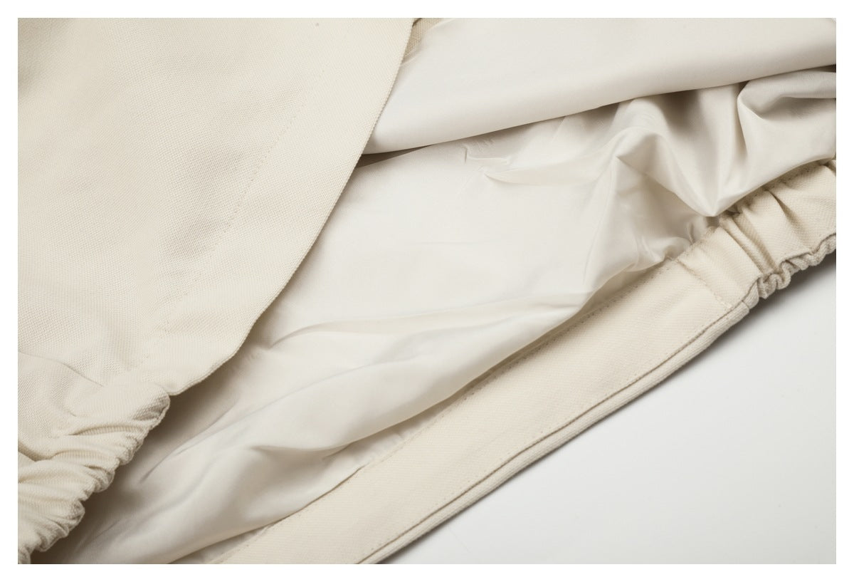 Close-up of ivory garment construction showing a smooth inner lining and gathered edge.