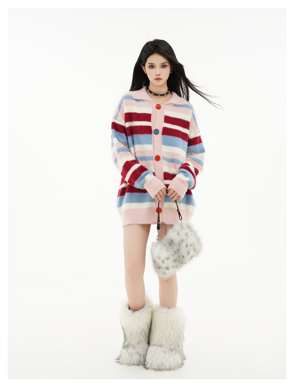 Full-length model in a pink cardigan with blue, burgundy, and cream stripes, holding a fuzzy bag and wearing furry boots.