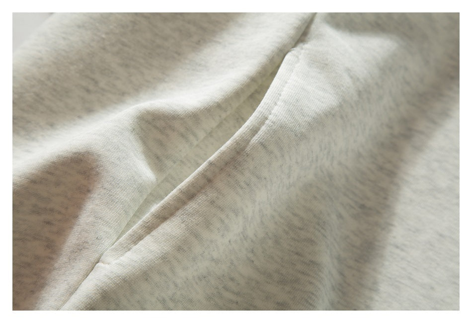 Close-up of a diagonal pocket opening and seam on a light gray heathered sweatshirt.