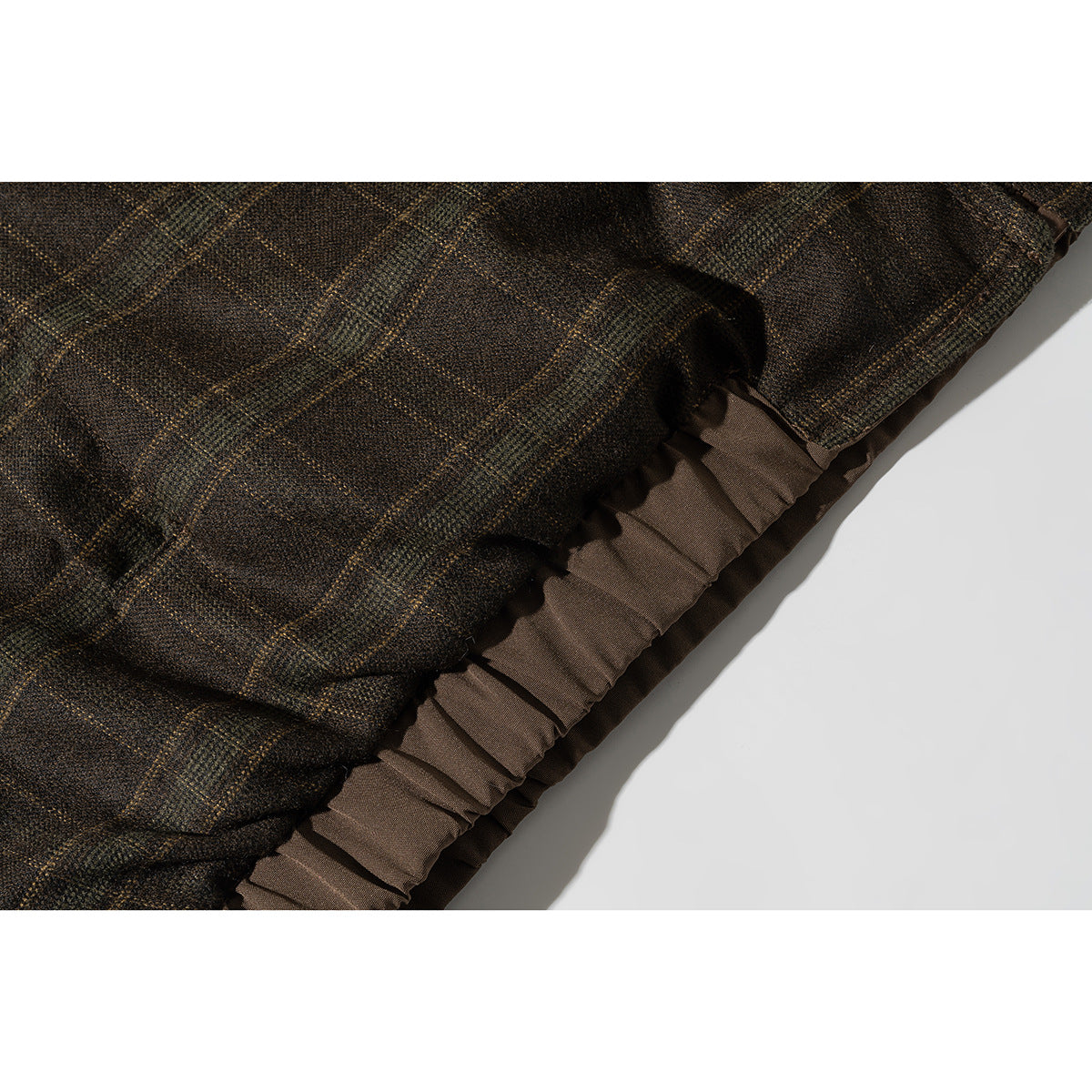 Close-up of brown plaid jacket fabric and a gathered brown lining edge.