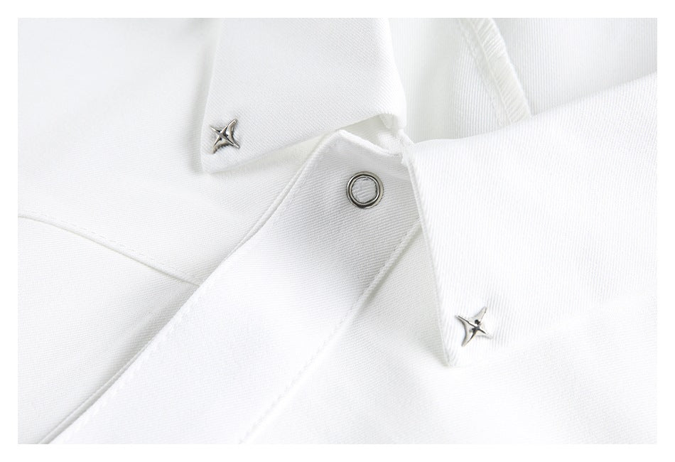 Close-up of a white garment with a metal snap fastener and two small star-shaped metal studs.