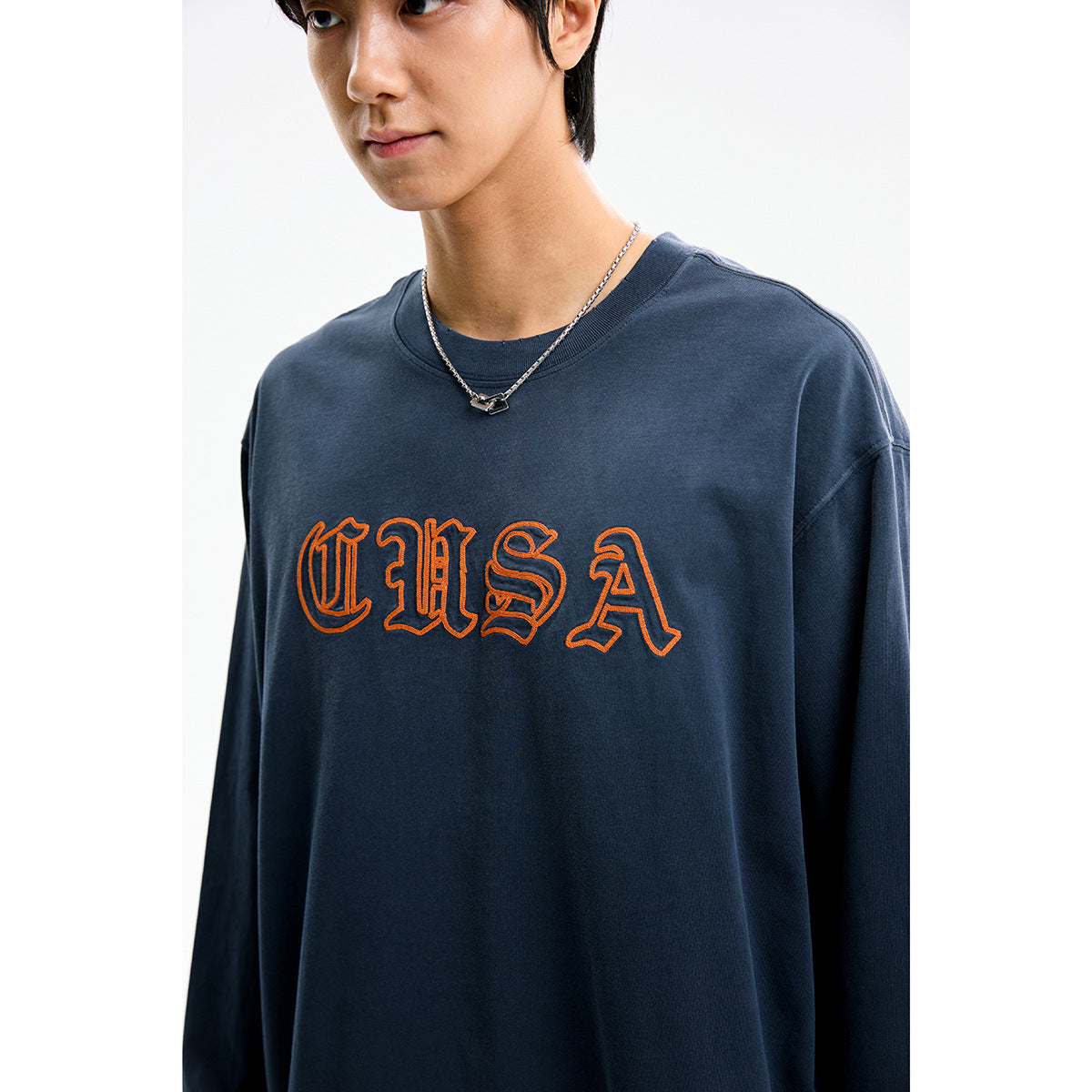 Close-up of a model wearing a navy long-sleeve shirt with large orange outlined USA lettering.