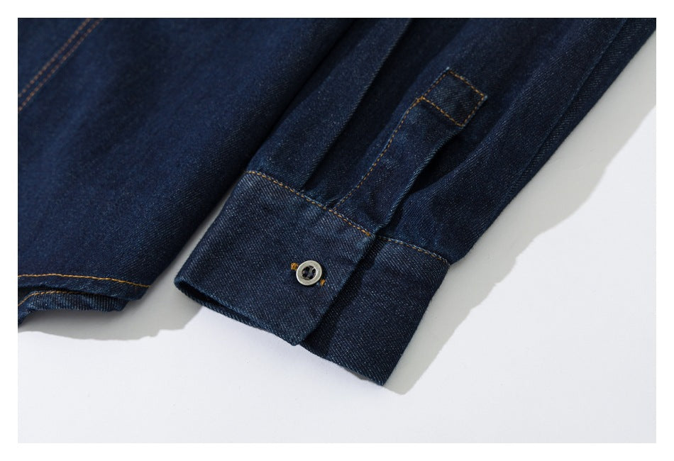 Close-up of a dark indigo denim shirt sleeve cuff with a button and contrast stitching.