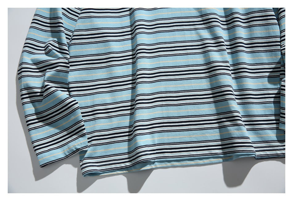 Flat-lay view of a light blue long-sleeve shirt with horizontal black, white, and thin tan stripes.