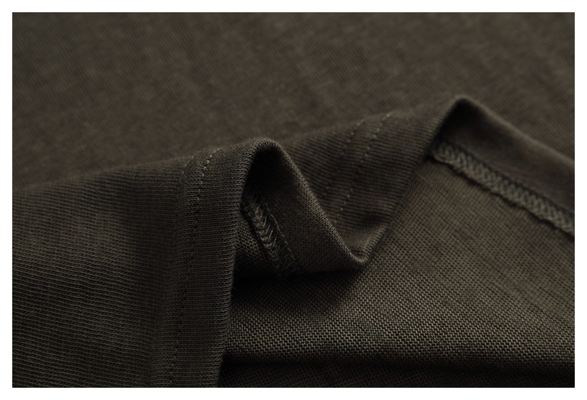 Close-up of dark charcoal-brown knit garment fabric, showing a folded edge and overlocked seam.
