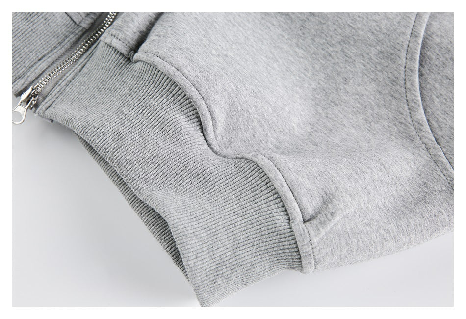 Close-up of a silver zipper beside a ribbed gray waistband and curved pocket seam.