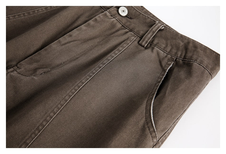 Close-up showing the dark brown pants' front pocket opening, waistband, button, and stitching.
