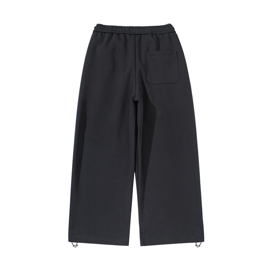 Back view of black wide-leg pants with an elastic waistband, one patch pocket and metal hem adjusters.