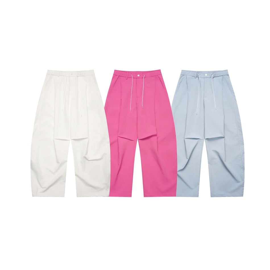 Front view of wide-leg pleated pants in white, bright pink, and pale blue.