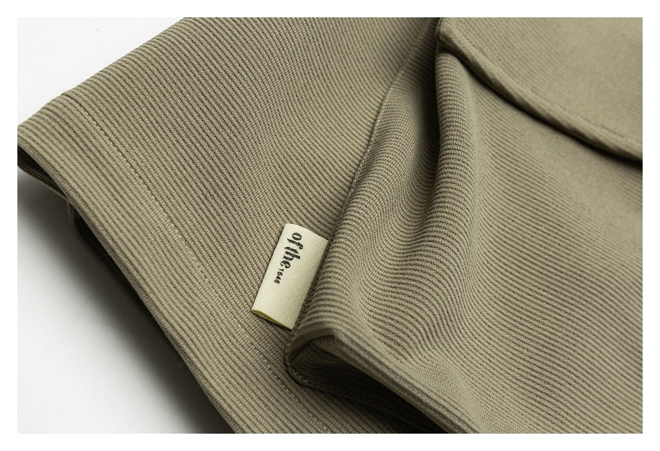 Close-up of olive-khaki ribbed fabric, seam stitching, and a small woven garment label.
