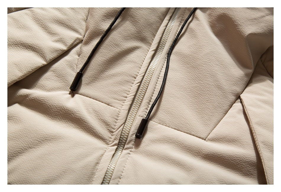 Close-up of the jacket's textured beige fabric, black hood drawcords, and front zipper.