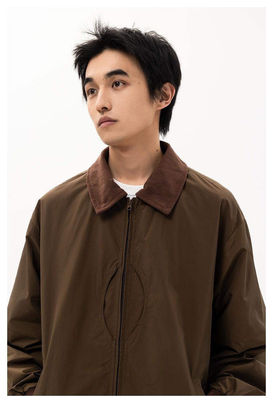 Close view of a male model wearing a dark brown jacket with a corduroy collar and central zipper.
