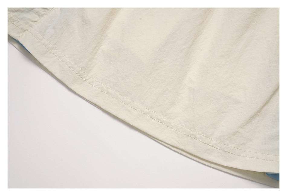 Close-up of the cream skirt's curved hem stitching with a glimpse of pale blue lining.
