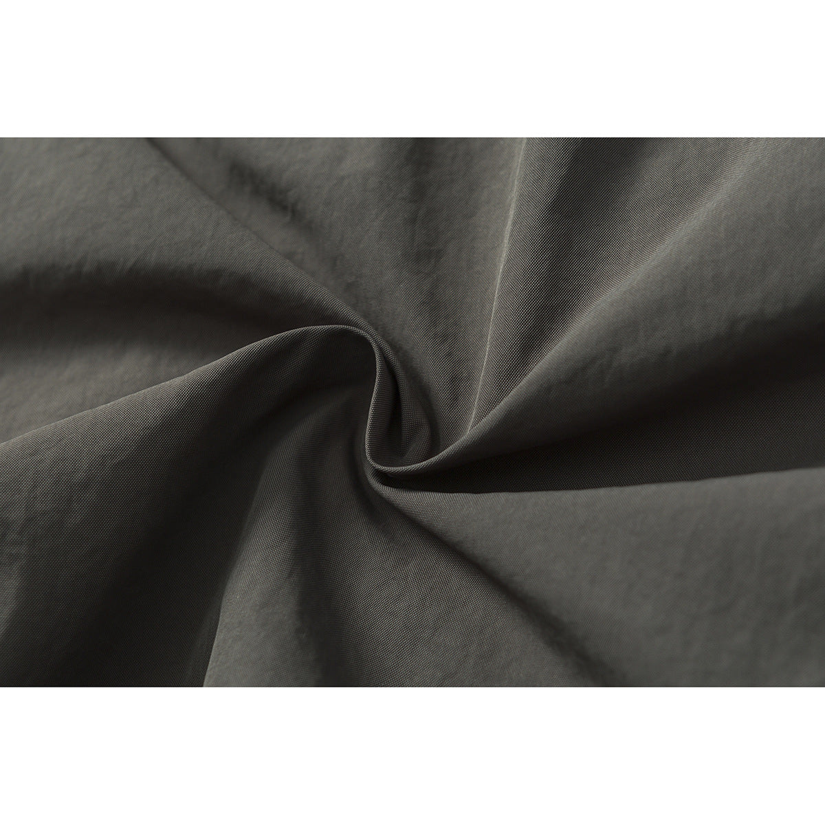 Macro view of dark gray fabric arranged in folds, showing its fine surface texture.