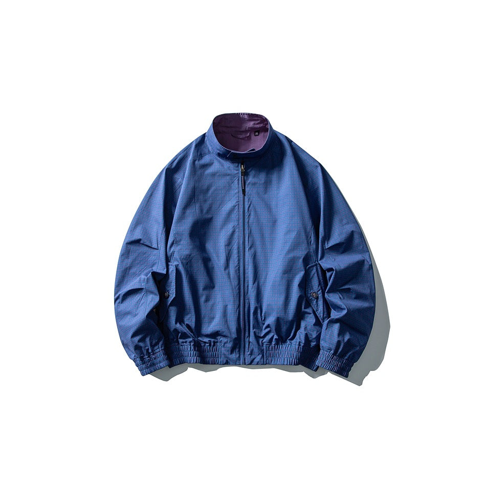 Prussian blue stand-collar zip jacket flat lay with purple reverse visible at collar