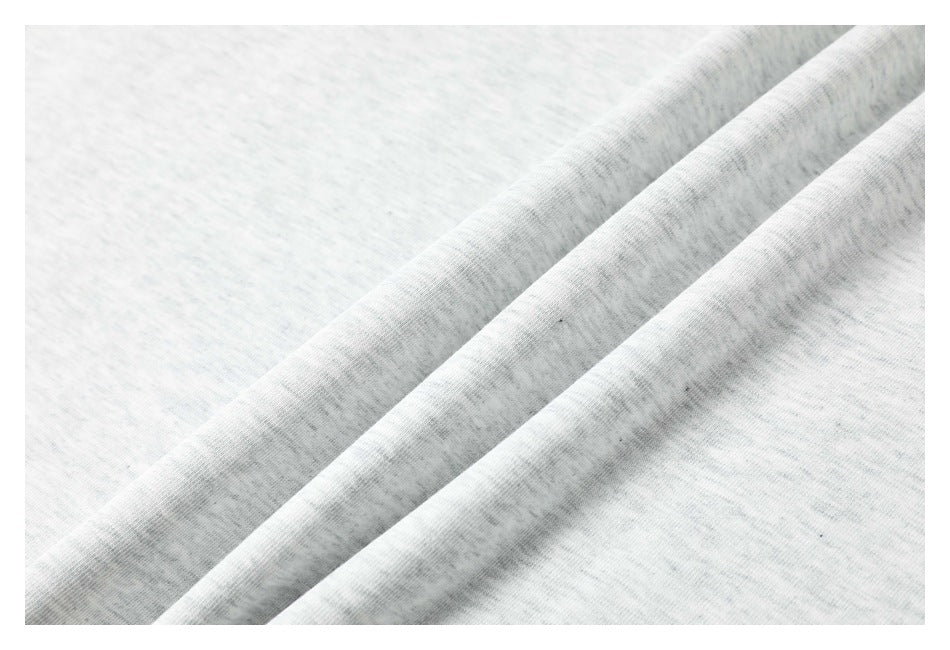 Close-up showing the light gray heather texture of a T-shirt fabric folded into soft ridges.