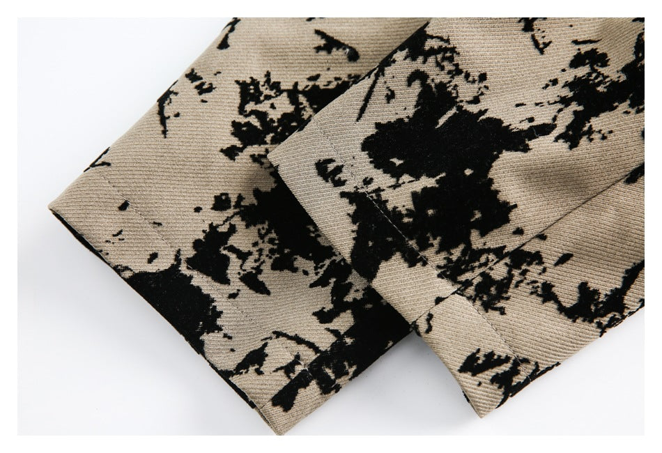 Close-up of overlapping folded edges and stitching on tan fabric with a black abstract floral pattern.