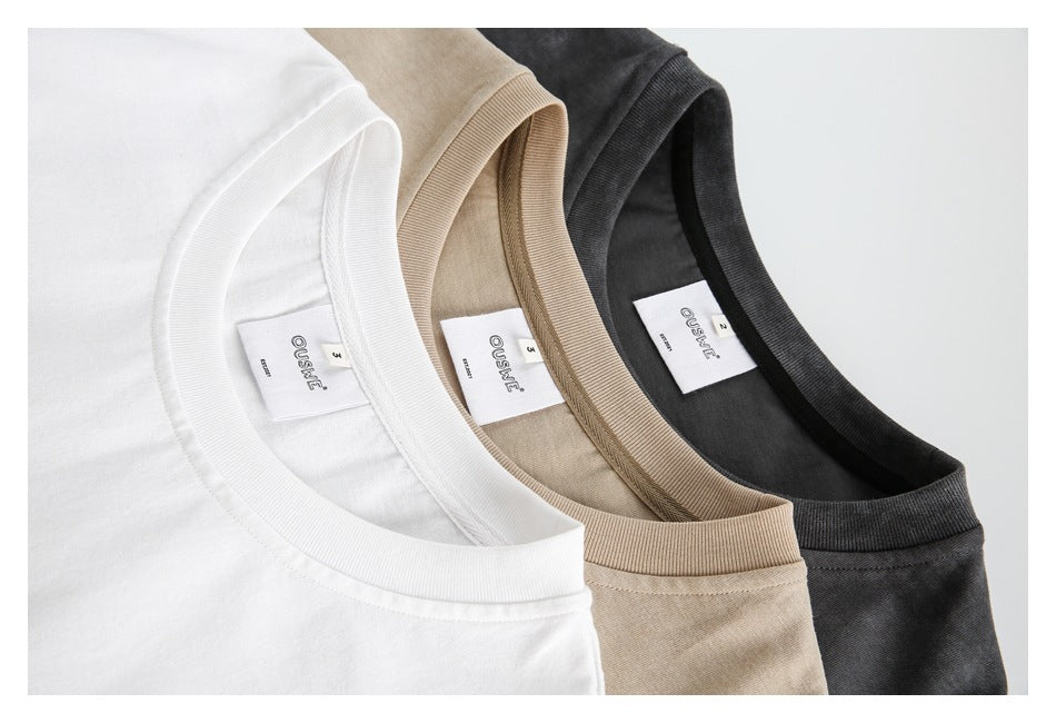 Close-up of white, beige, and charcoal sleeveless shirts showing their necklines and inner labels.