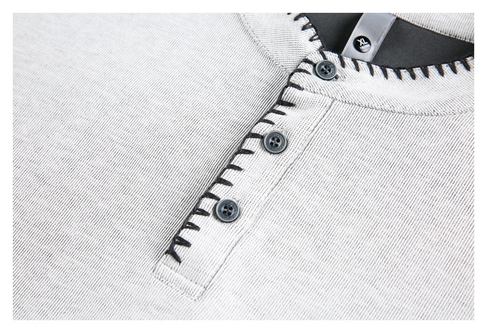 Close-up of a light gray shirt's three-button placket and neckline with black contrast stitching.