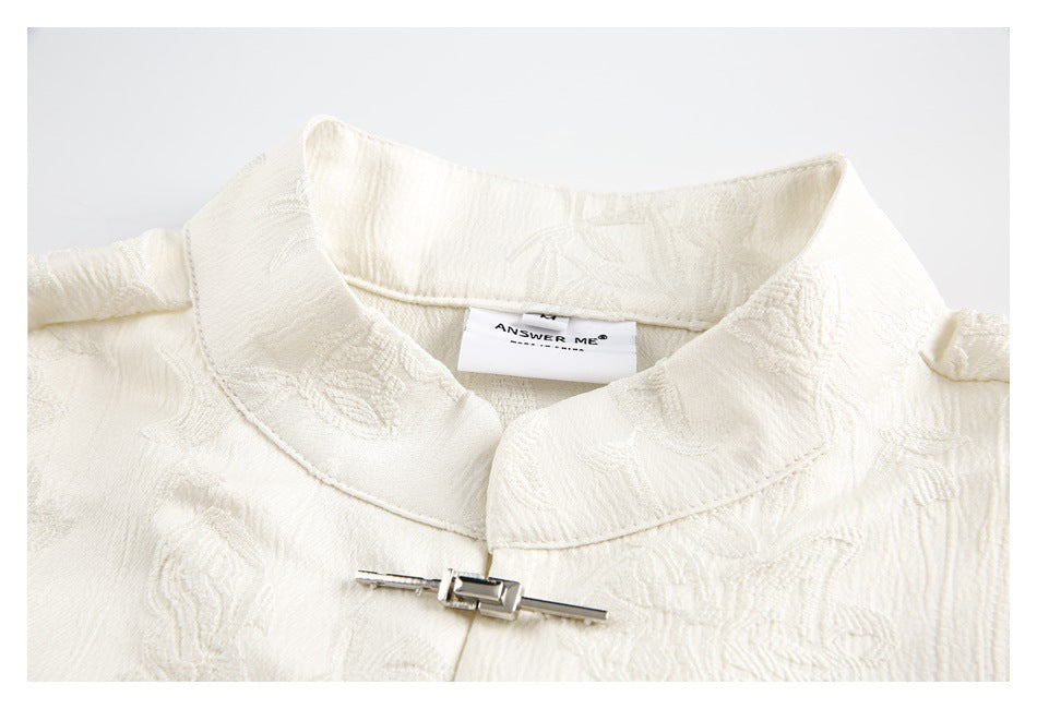 Close-up of an ivory floral shirt collar with a metal clasp and sewn-in neck label.