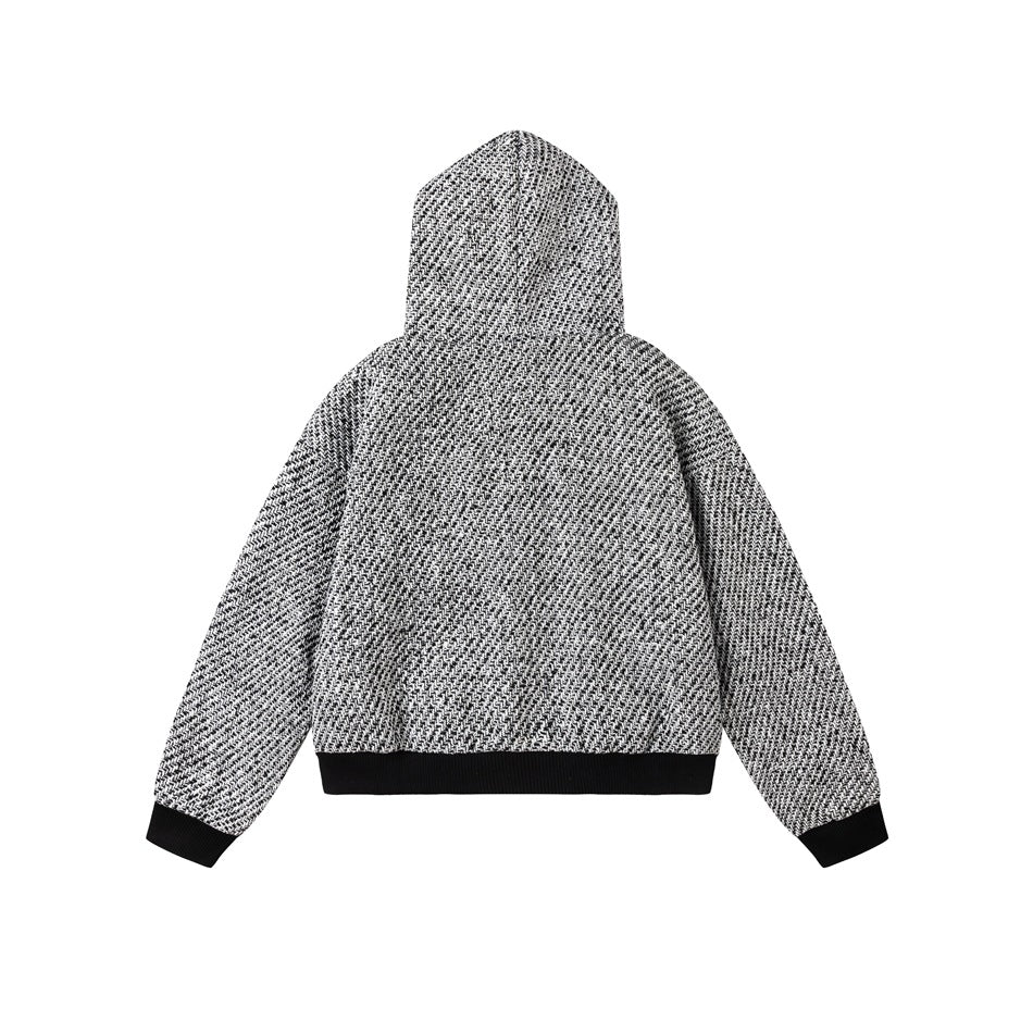 Back view of a black-and-white patterned hooded jacket laid flat, with black ribbed cuffs and hem.